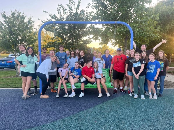 students sitting on park bench smiling