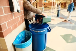 student putting recycling in a bin